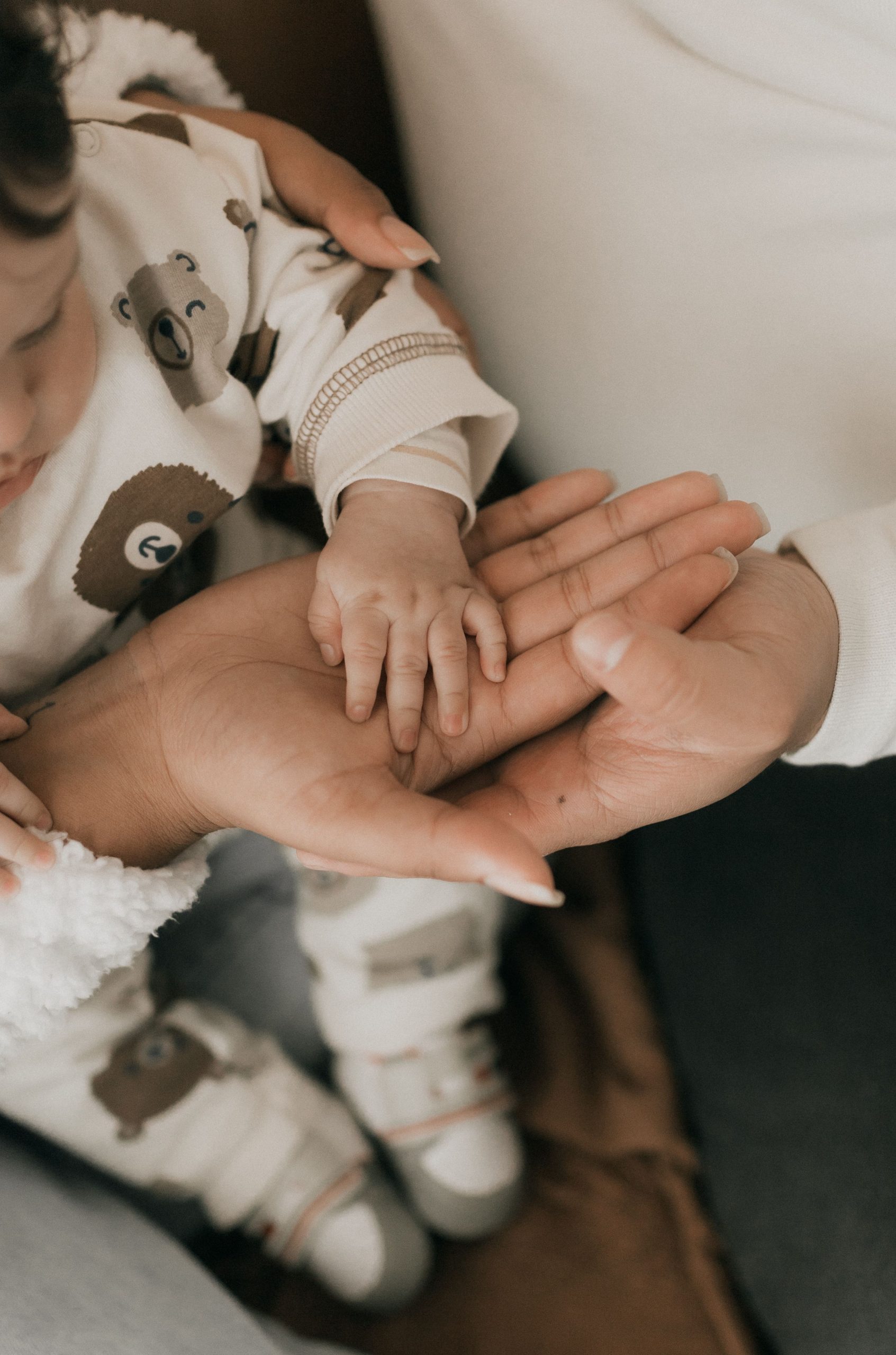 Close-up of a mother holding her baby's hand, symbolizing love and care.
